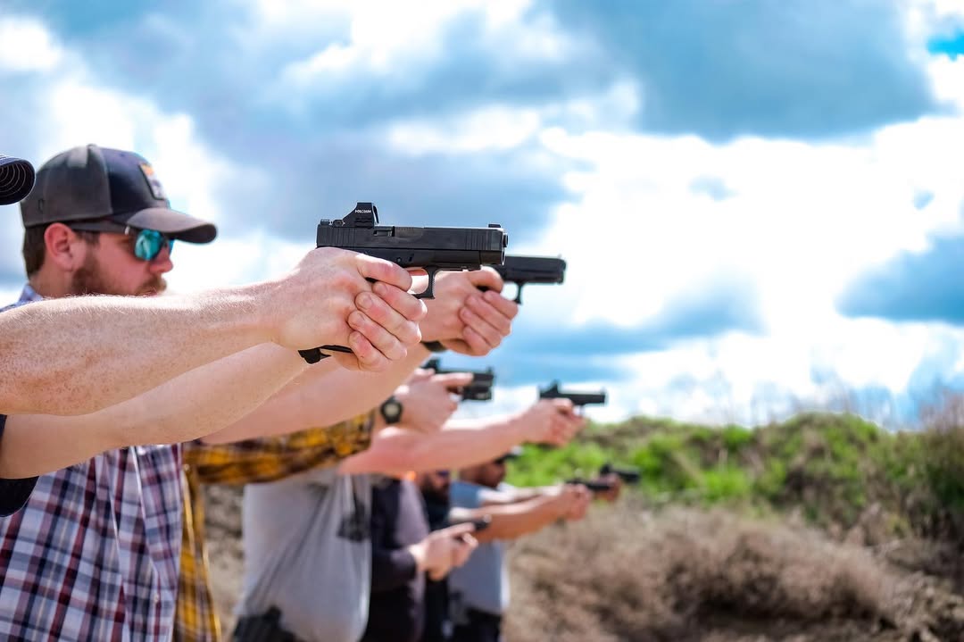 Men at an outdoor shooting range practicing handgun shooting.