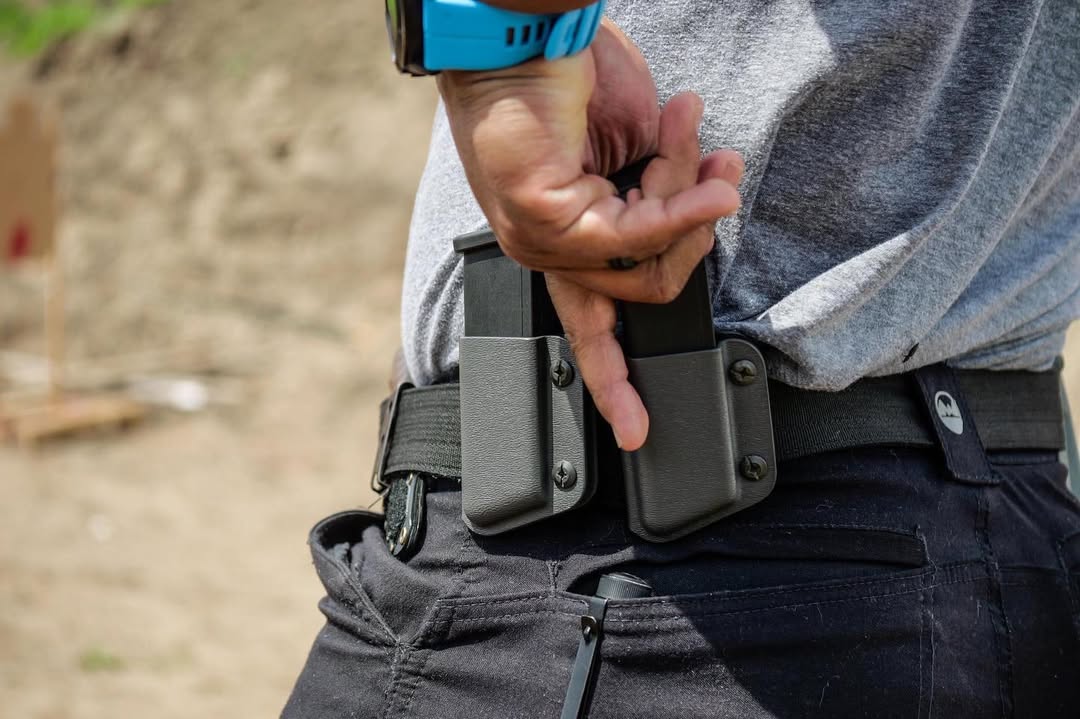 Someone demonstrating how to draw a magazine from a holster during a firearm training session.