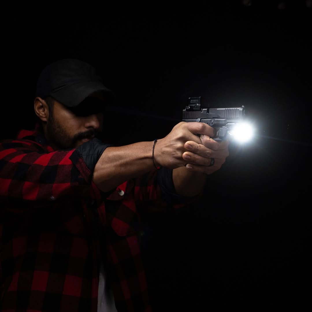 Man demonstrating a flashlight and weapon mounted light during a night time self defence training drill.