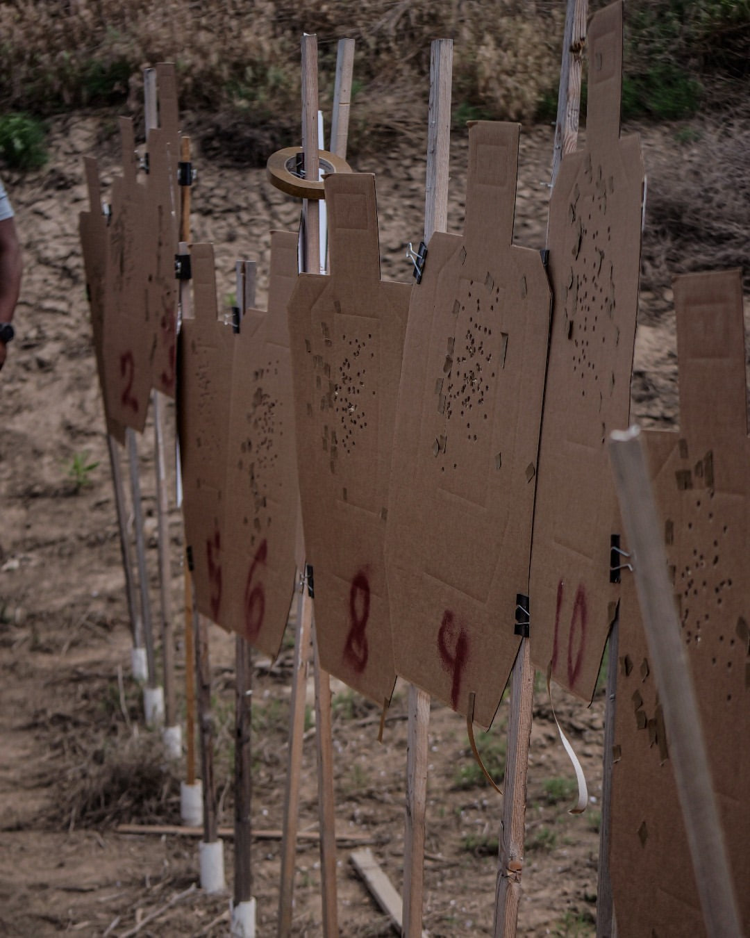 Cardboard targets in a line at an outdoor shooting range.