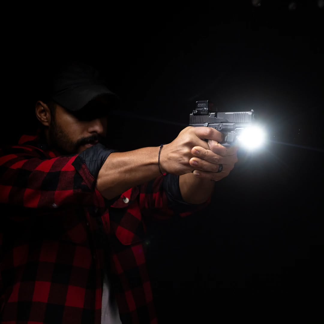 Man aiming a handgun at night with a torch.