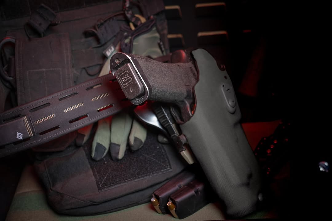 Tactical handgun with magazine extension and glared magwell in a holster.